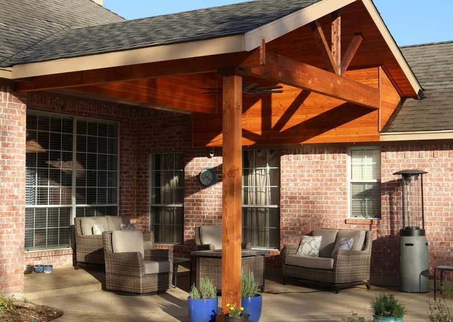 Covered patio with wicker outdoor furniture attached to a single-story brick home