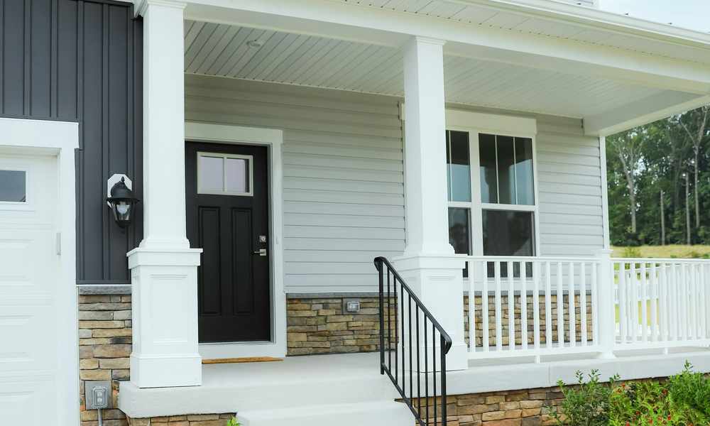 Two-story home exterior with light gray horizontal siding, dark vertical accent siding, and a covered front porch